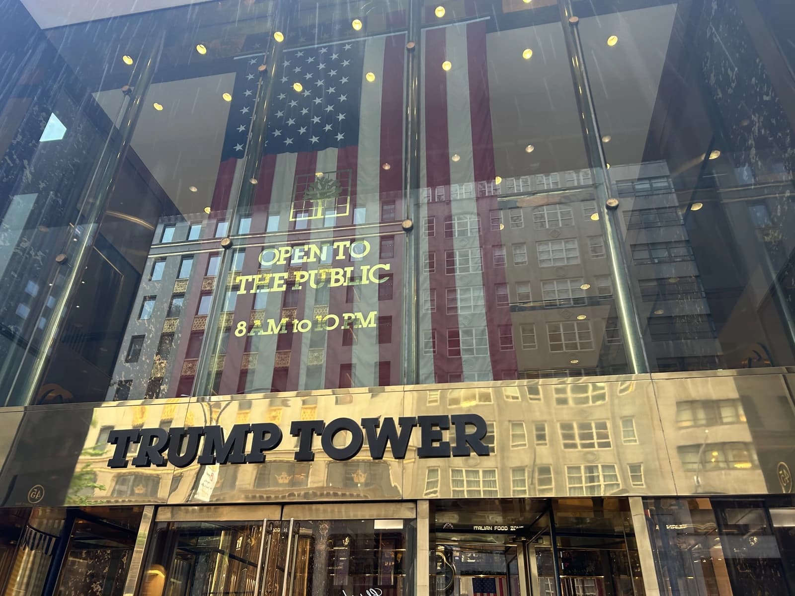 Trump Tower exterior showing the building sign and reflection of an American flag.