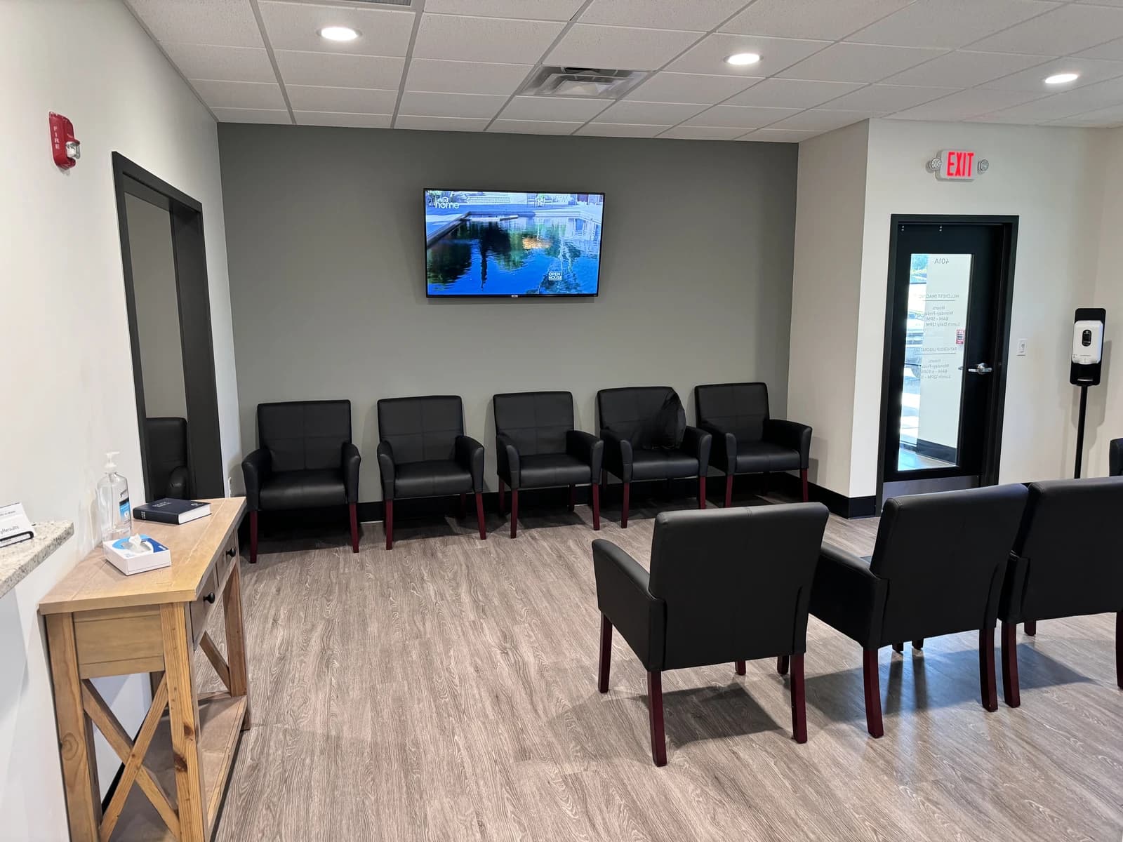Empty waiting room with black chairs and a television in a medical clinic.