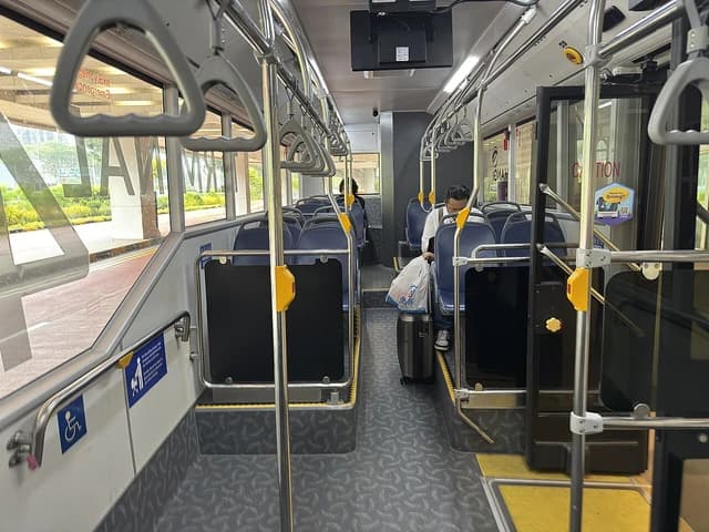 Passenger sitting with luggage inside a Woodlands Transport Singapore Changi Airport shuttle bus.