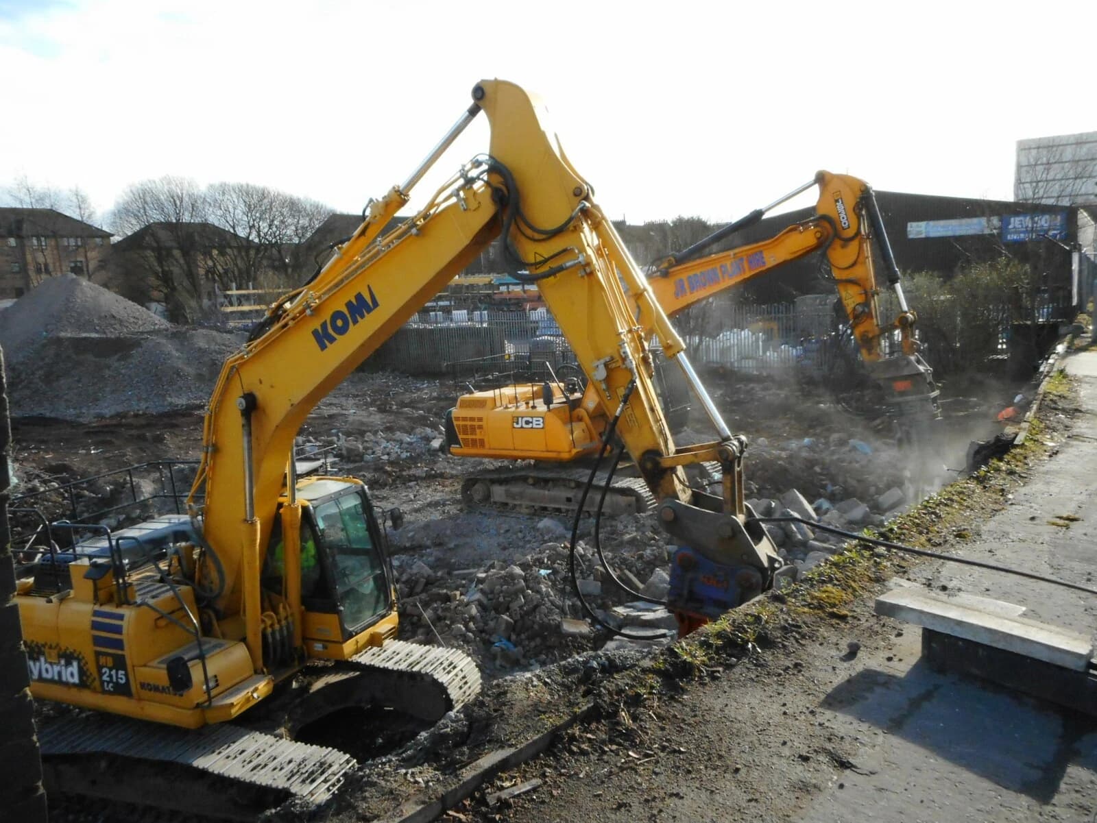 Two yellow excavators with hydraulic breakers working on a construction or demolition site.