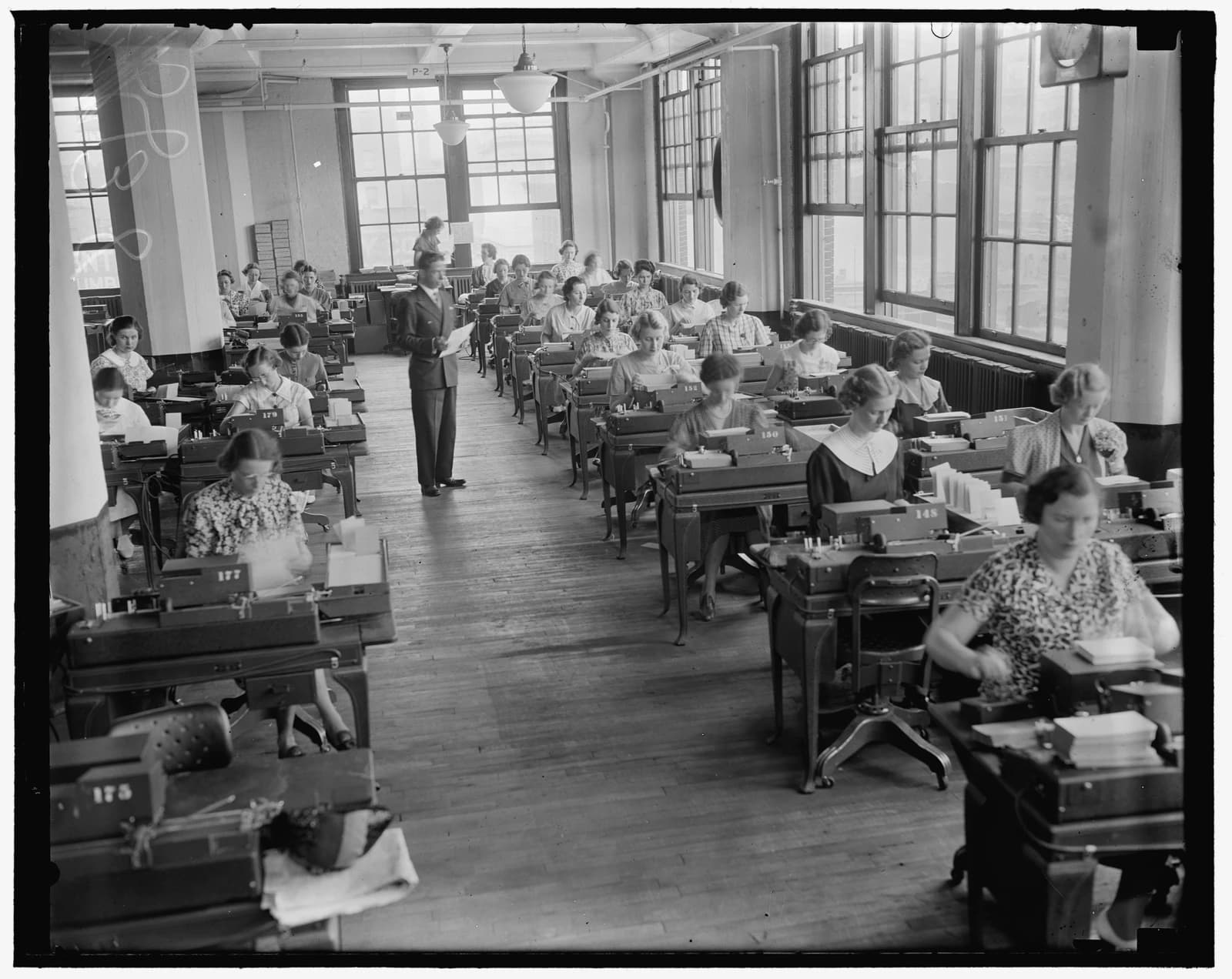 Employees in an office setting operating early data processing machines for Social Security records.