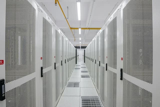Rows of white server racks line an aisle in the Amravati Data Center.