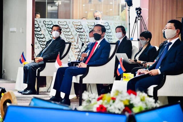 Indonesian President Joko Widodo sits with other masked leaders at a conference table.