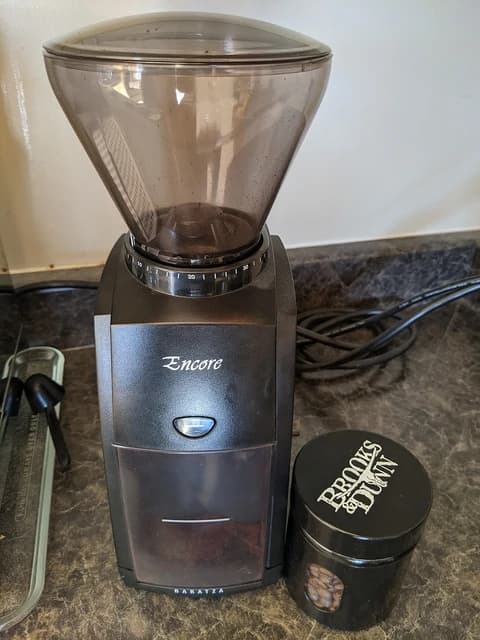 Baratza Encore burr coffee grinder and a small container of whole coffee beans.