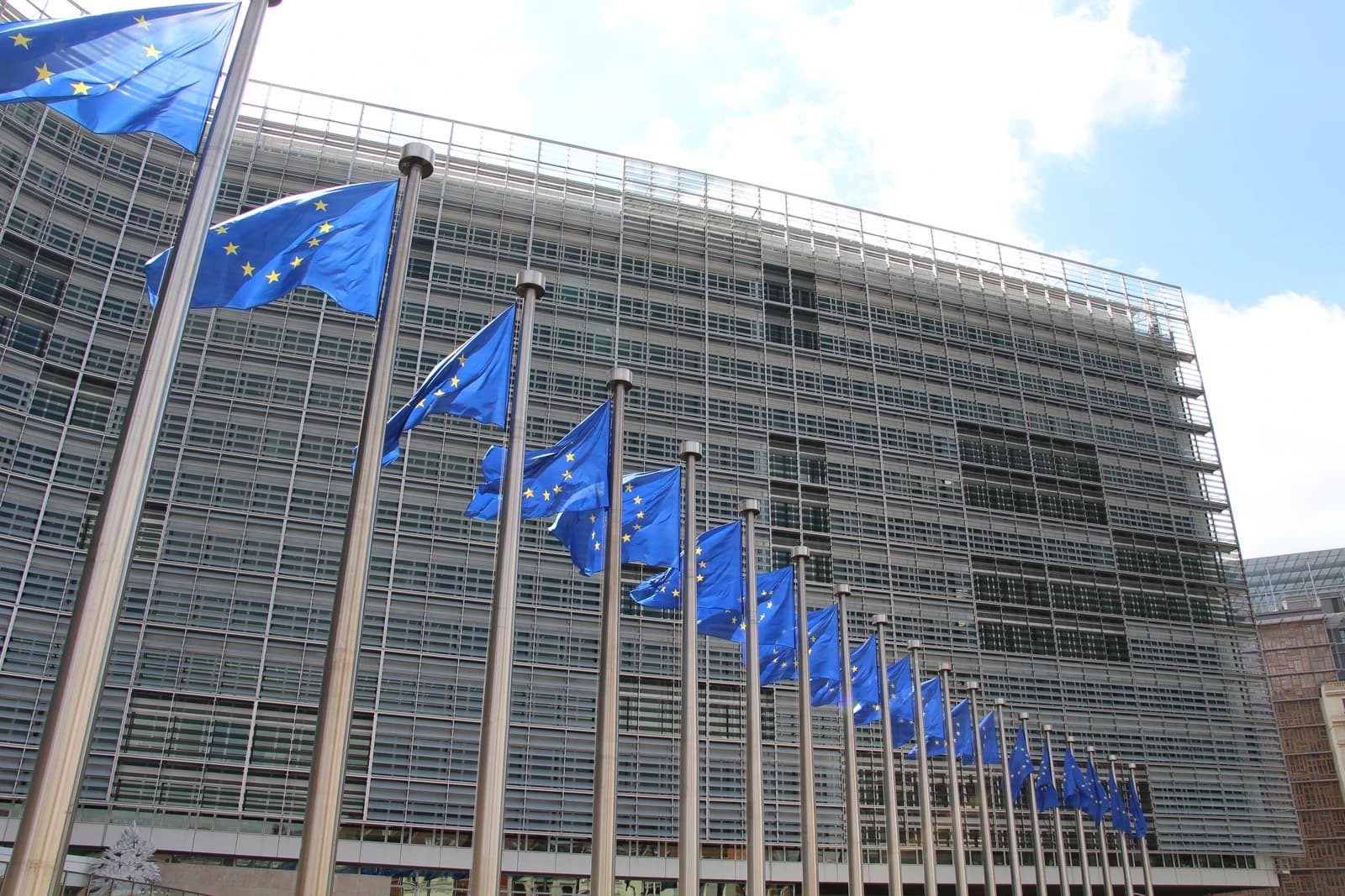 European Union flags on poles in front of the Berlaymont building in Brussels.