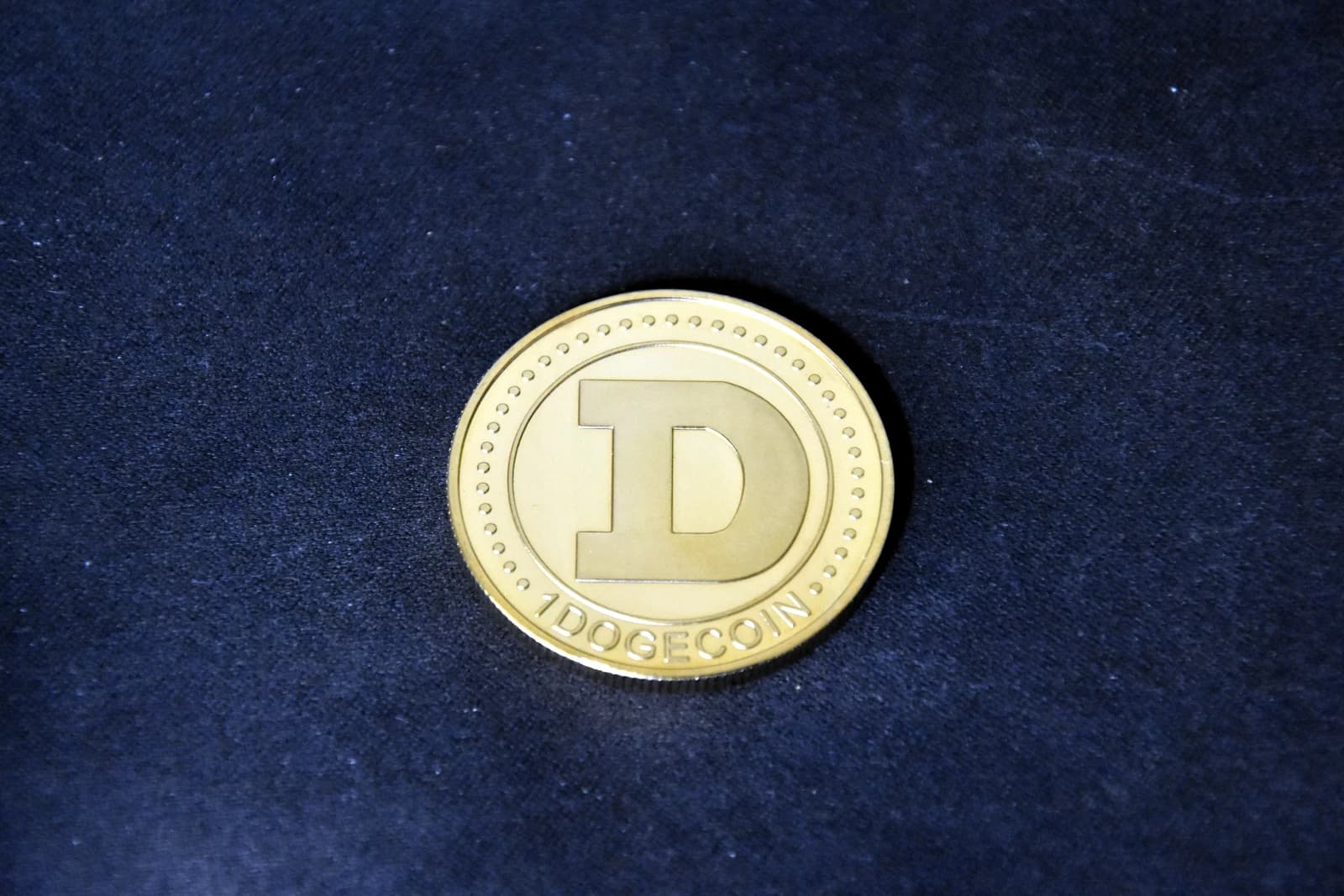 A gold-colored Dogecoin, displaying the letter 'D' and '1 DOGECOIN' on its surface.