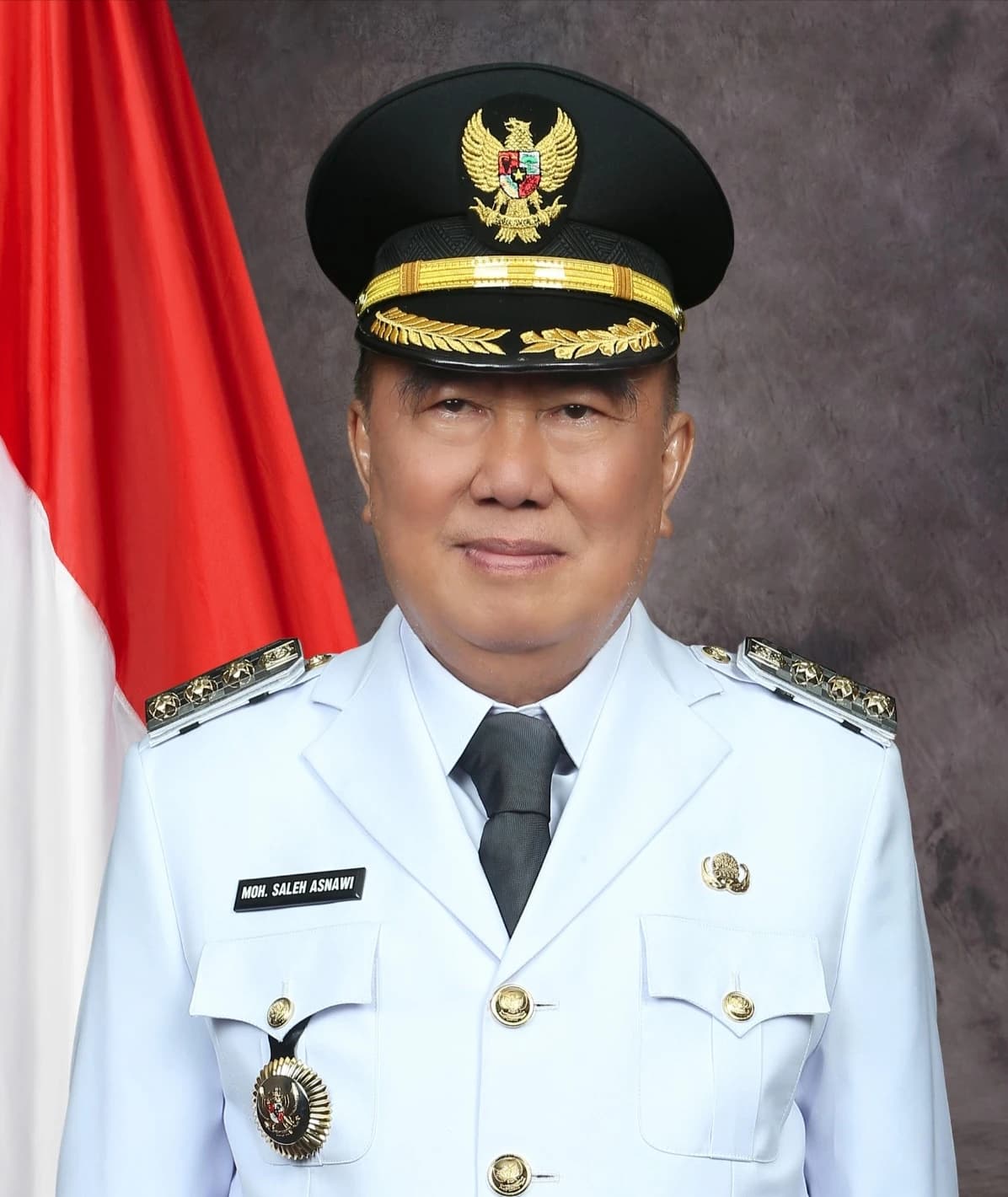 Mohammad Saleh Asnawi, Regent of Tanggamus, in an official portrait with Indonesian flag.