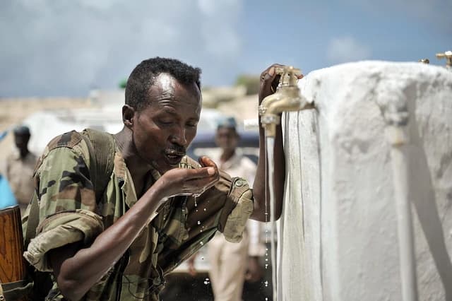 A member of the Somali National Army drinks water from a communal tap.
