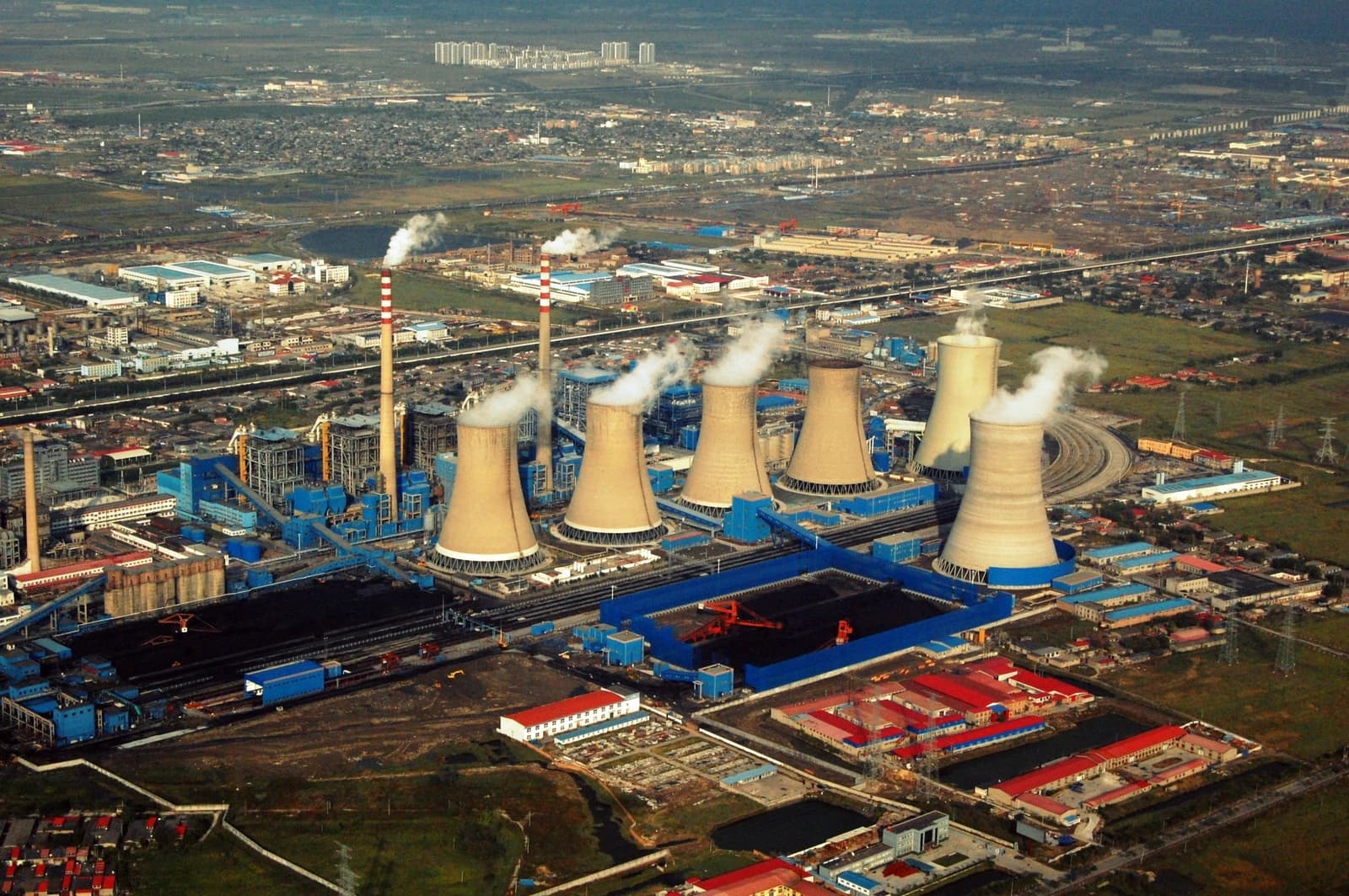 Aerial view of a large power plant with multiple cooling towers and smokestacks in Tianjin, China.