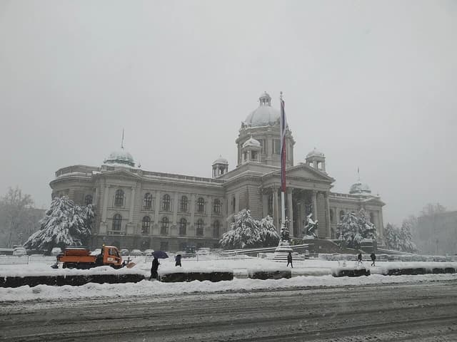 The National Assembly of Serbia building covered in snow during winter.