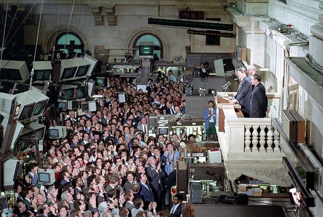 President Ronald Reagan speaks from a podium on a balcony to employees at the New York Stock Exchange.