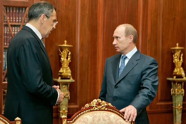 Russian President Vladimir Putin speaks with Foreign Minister Sergey Lavrov in an office.