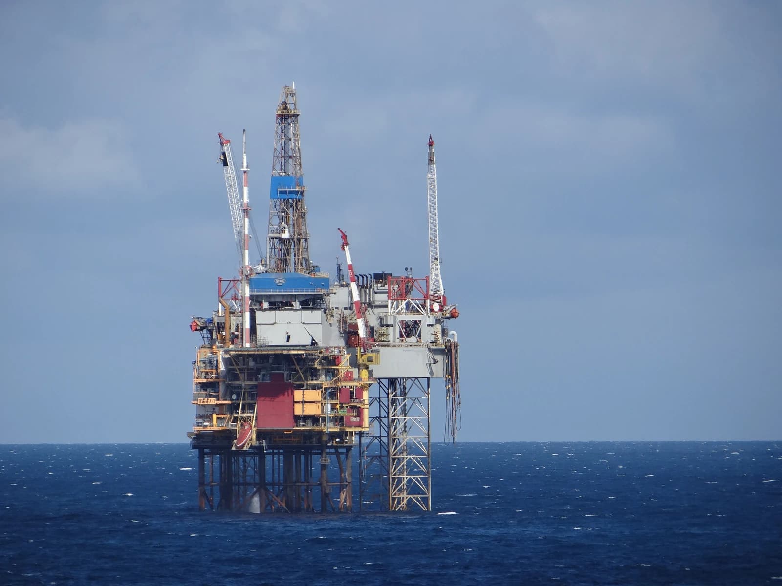 An offshore oil rig stands in the North Sea, under a blue sky.