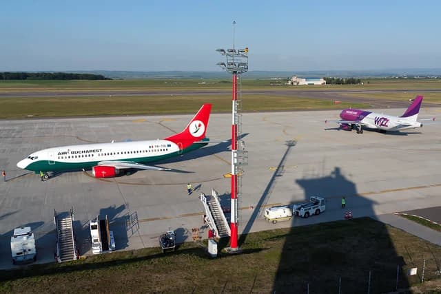 Air Bucharest and Wizz Air aircraft on an airport tarmac under clear skies.