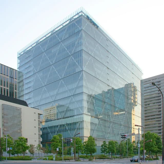 Sony headquarters, a modern glass building, standing tall next to a street.