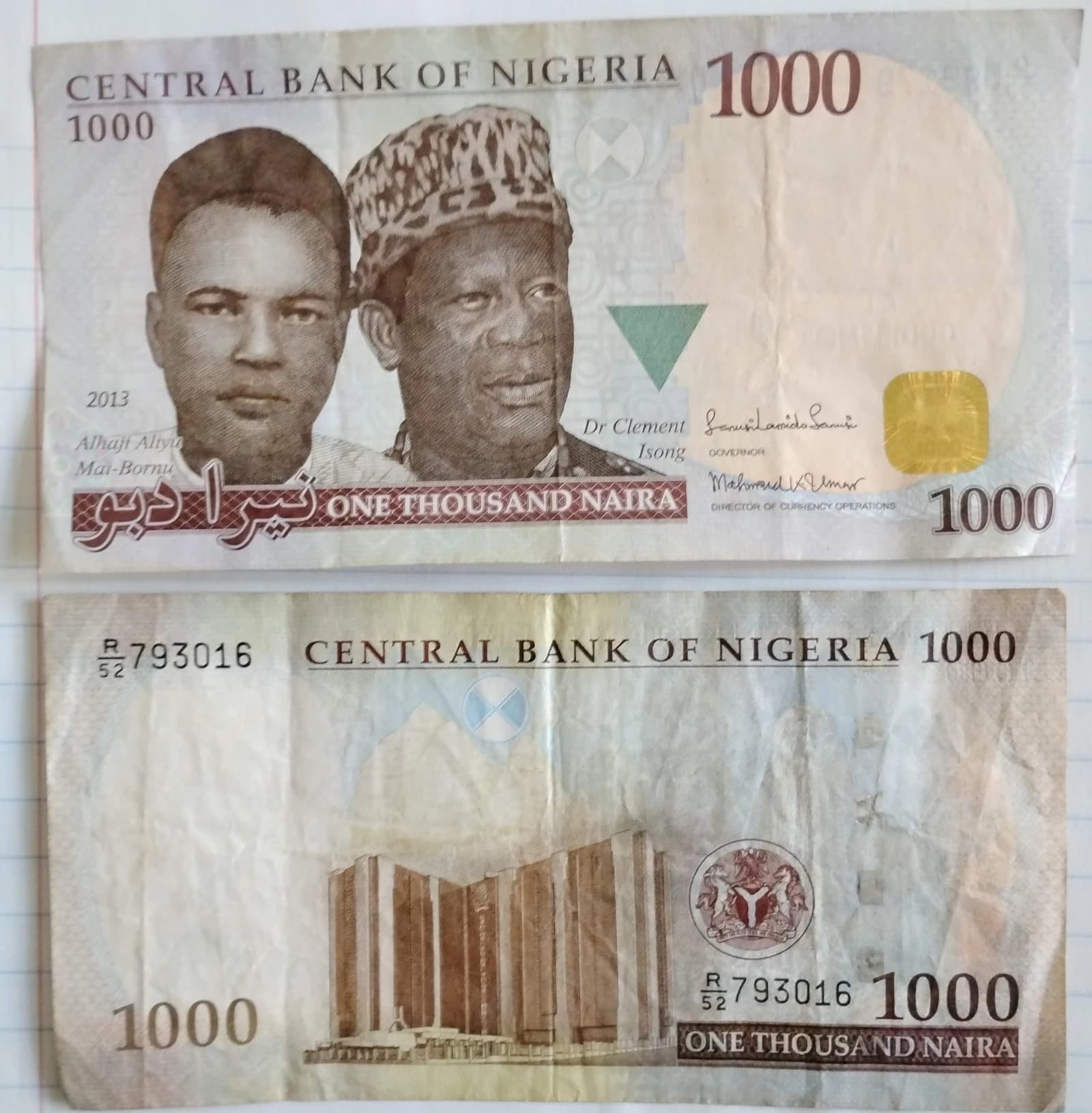 Close-up of a Nigerian 1000 Naira banknote, front and back sides displayed.