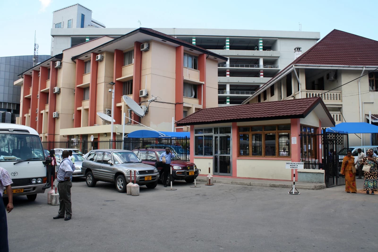 Tanzania Ministry of Finance headquarters building exterior with people and parked cars.