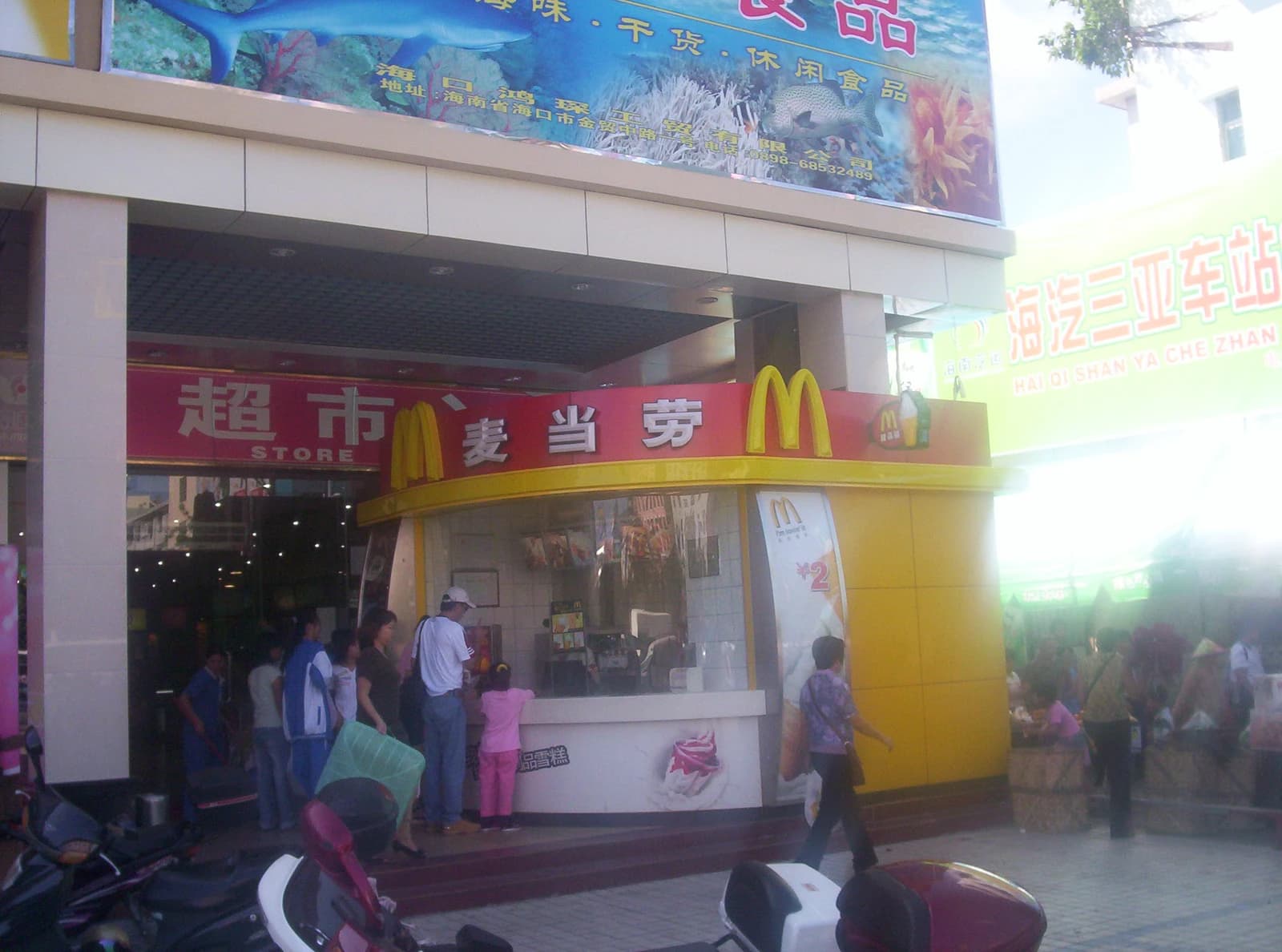People stand and walk outside a McDonald's restaurant in Sanya, China.