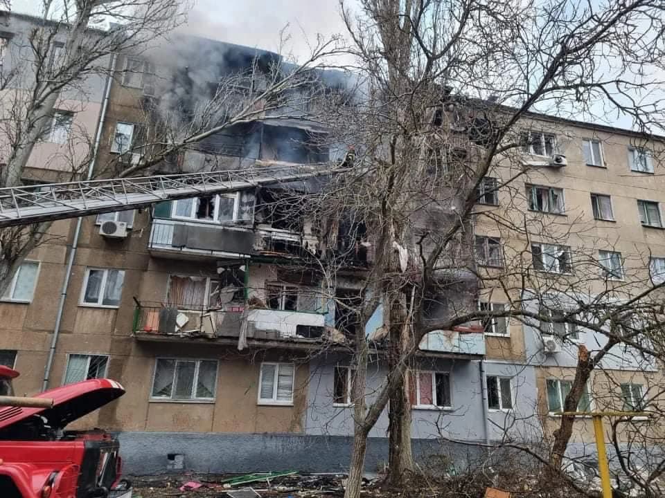 Residential building in Mykolaiv showing fire damage and smoke, with a fire ladder extended.