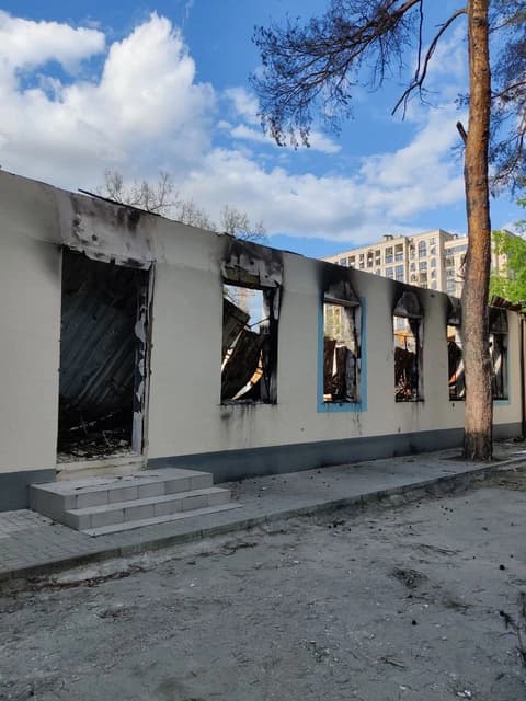 Exterior of a destroyed school building with burnt-out windows and entrance in Irpin, Ukraine.