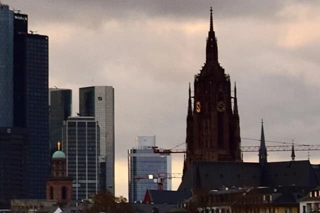 Skyscrapers, including Deutsche Bank, and a historic church tower in Frankfurt am Main.