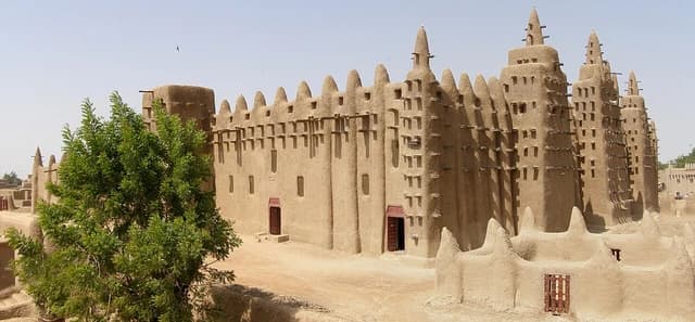 Exterior of the Great Mosque of Djenné, a large, sand-colored mud-brick building.