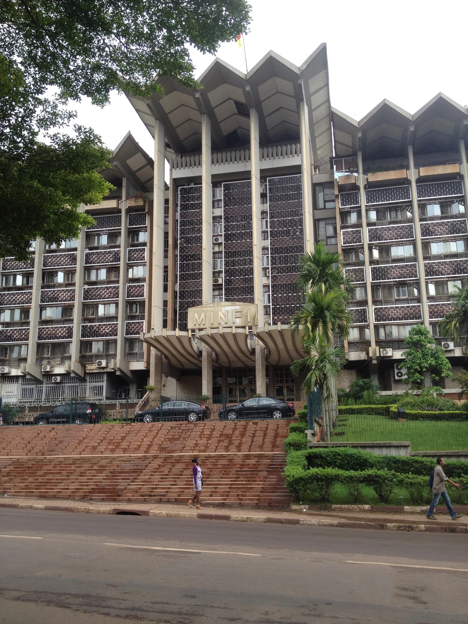 The Ministry of Finance building in Yaoundé, Cameroon, with people walking nearby.
