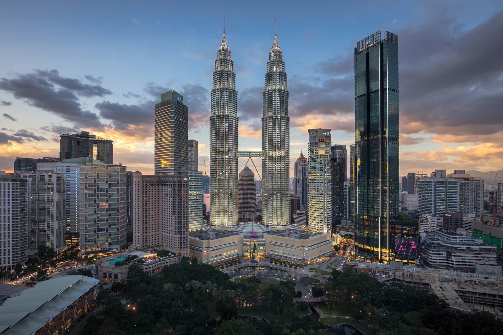Petronas Twin Towers and surrounding skyscrapers in Kuala Lumpur, Malaysia at dusk.