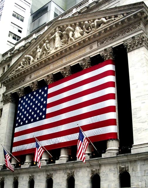Exterior of the New York Stock Exchange building adorned with American flags.