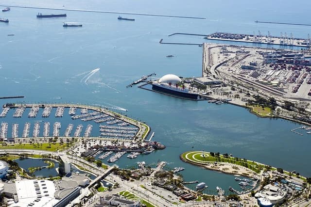 Aerial view showing cargo ships, shipping terminals, and surrounding marina at Port of Long Beach.