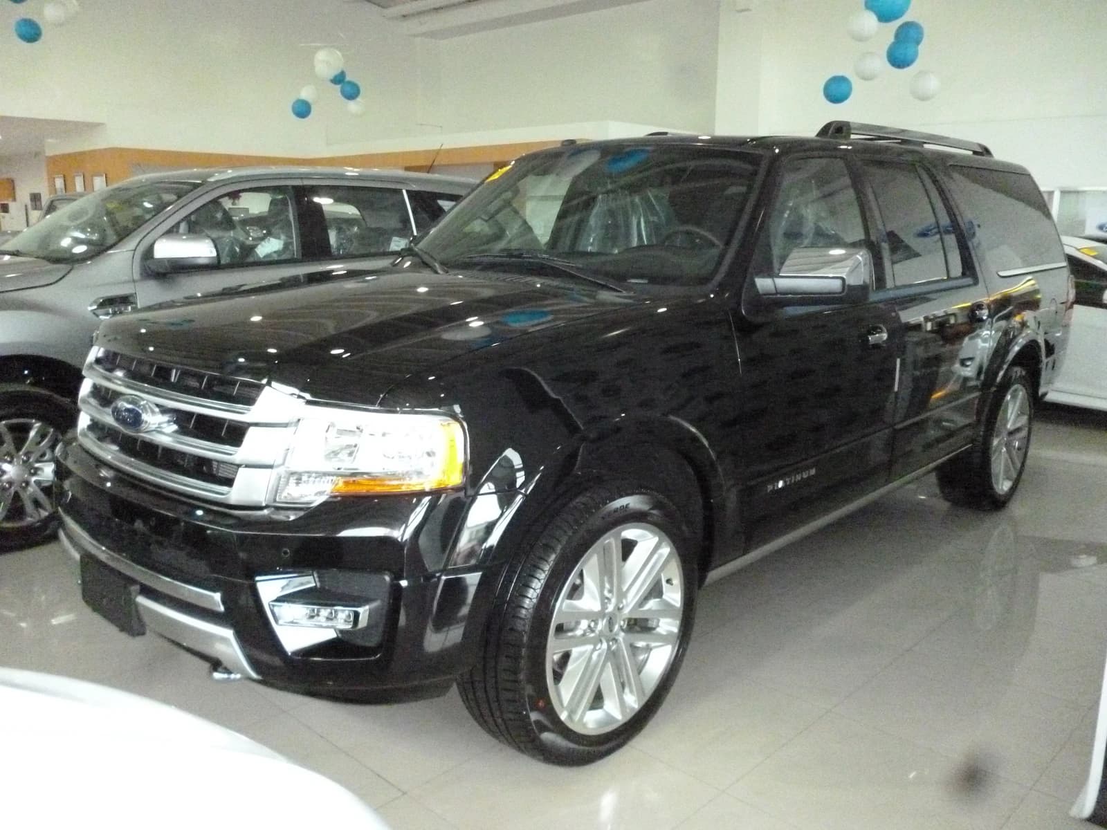 Black Ford Expedition 4x4 Platinum 2016 model SUV displayed inside a dealership.