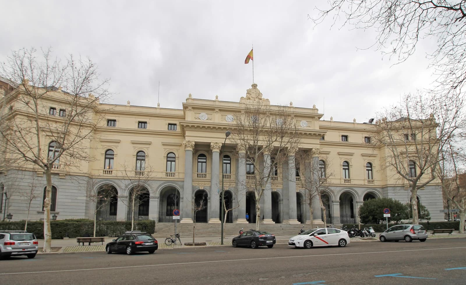 Exterior of the Palacio de la Bolsa de Madrid, a large building with columns and a Spanish flag.