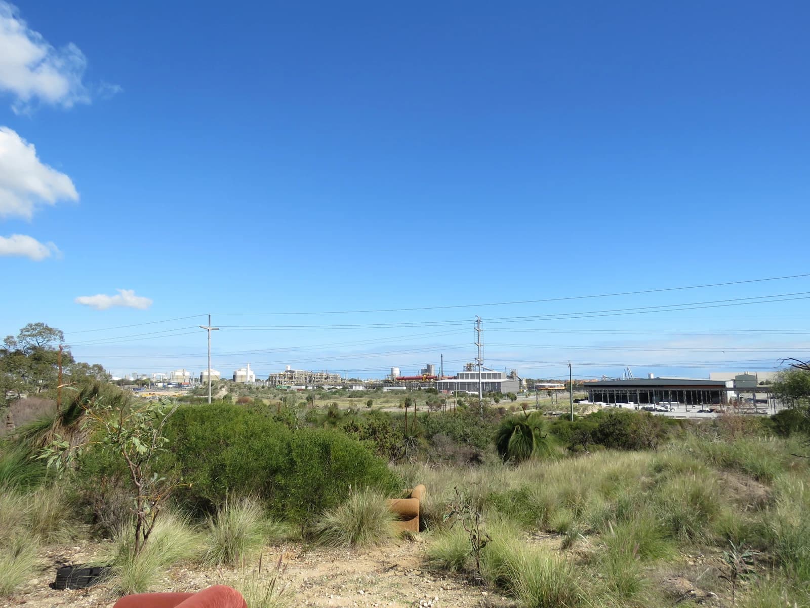 An industrial plant with multiple buildings and structures under a clear blue sky.