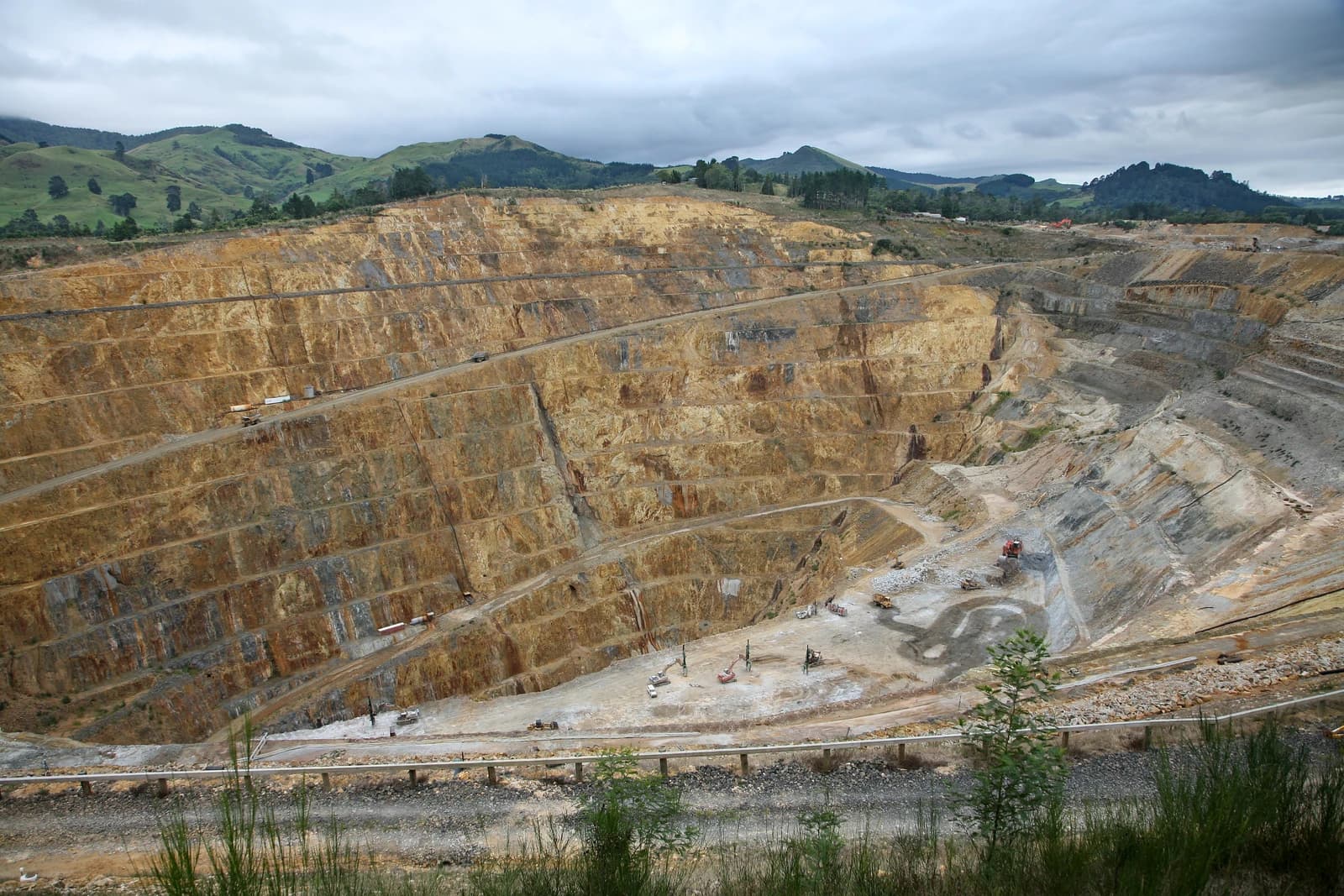 Open-pit gold and silver mine in New Zealand with terraced rock formations.