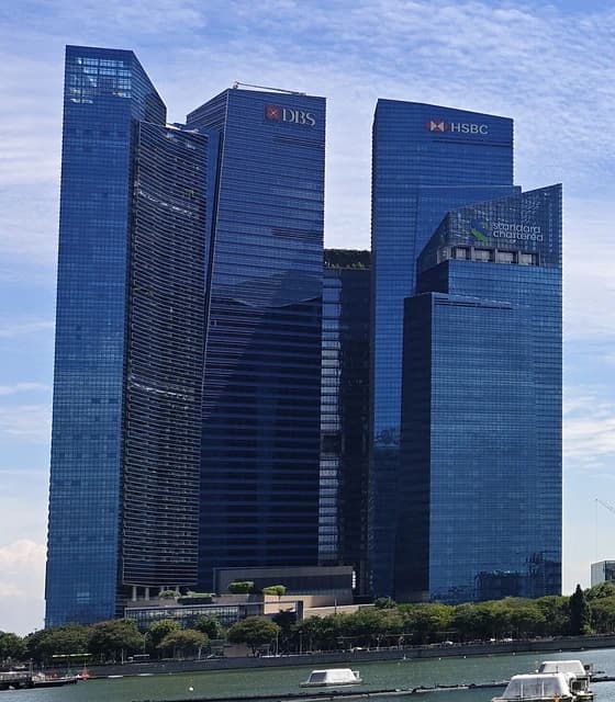 Skyscrapers of Marina Bay Financial Centre in Singapore against a partly cloudy sky.