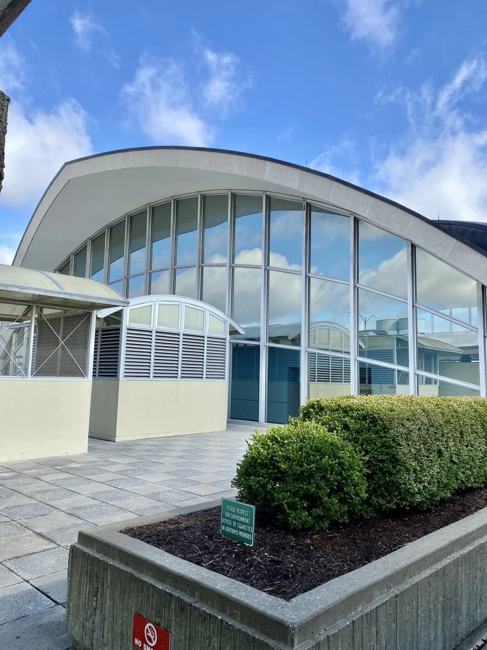 Terminal 1 building with a curved roof and large glass windows reflecting the sky.