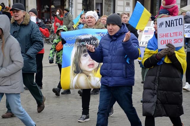 Protesters in Kraków, Poland, carrying signs and a large banner with a child's face.
