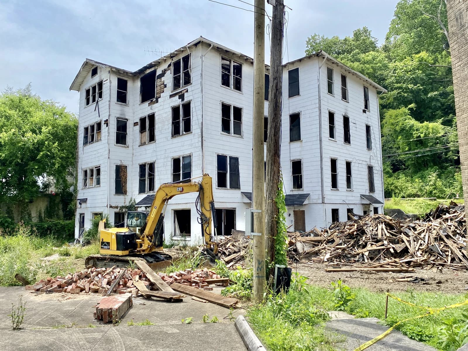 Old apartment building in disrepair with an excavator next to piles of debris in Middlesboro, Kentucky.