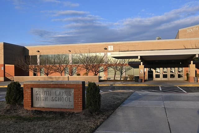 Entrance sign of South Lakes High School with the school building in the background.