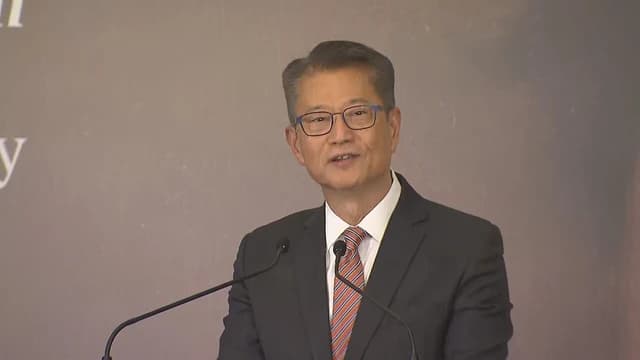 Paul Chan, Financial Secretary of Hong Kong, speaking at a podium.