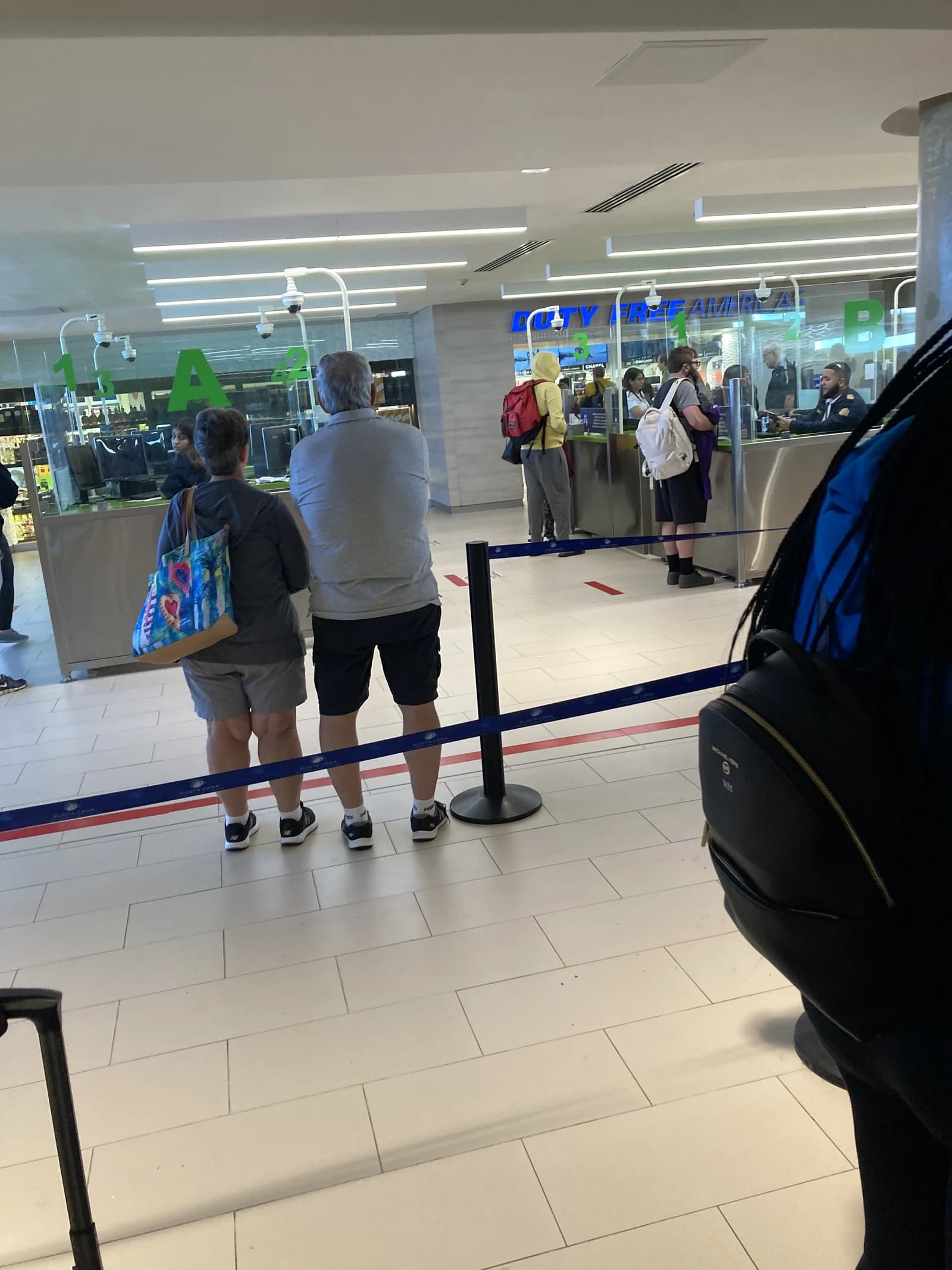 Travelers queuing at immigration counter inside Punta Cana Airport building.