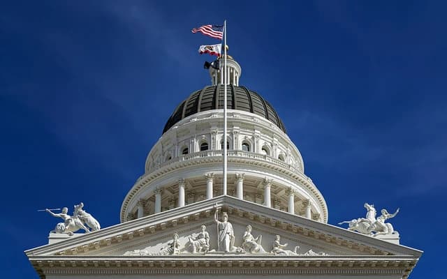 California State Capitol building dome with US and state flags, seen from the northwest.