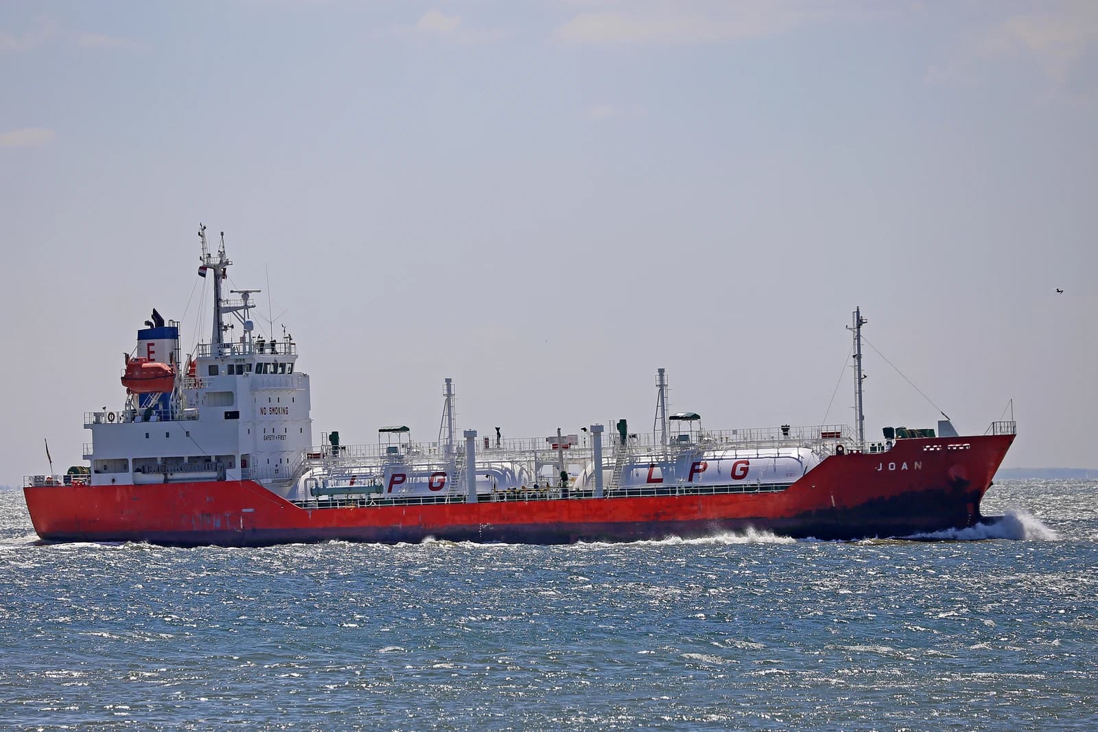 An LPG liquid gas tanker, named JOAN, sails on the open water.