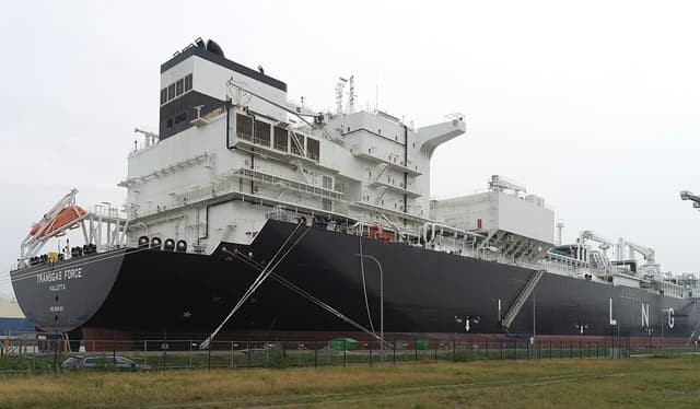 Large black and white LNG carrier 'Transgas Force' docked at a port.