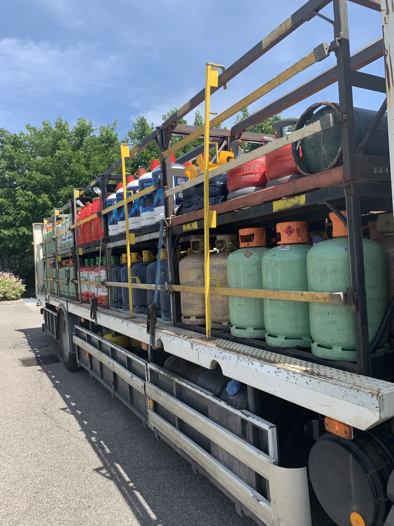 Delivery truck carrying multiple LPG gas cylinders of different colors.