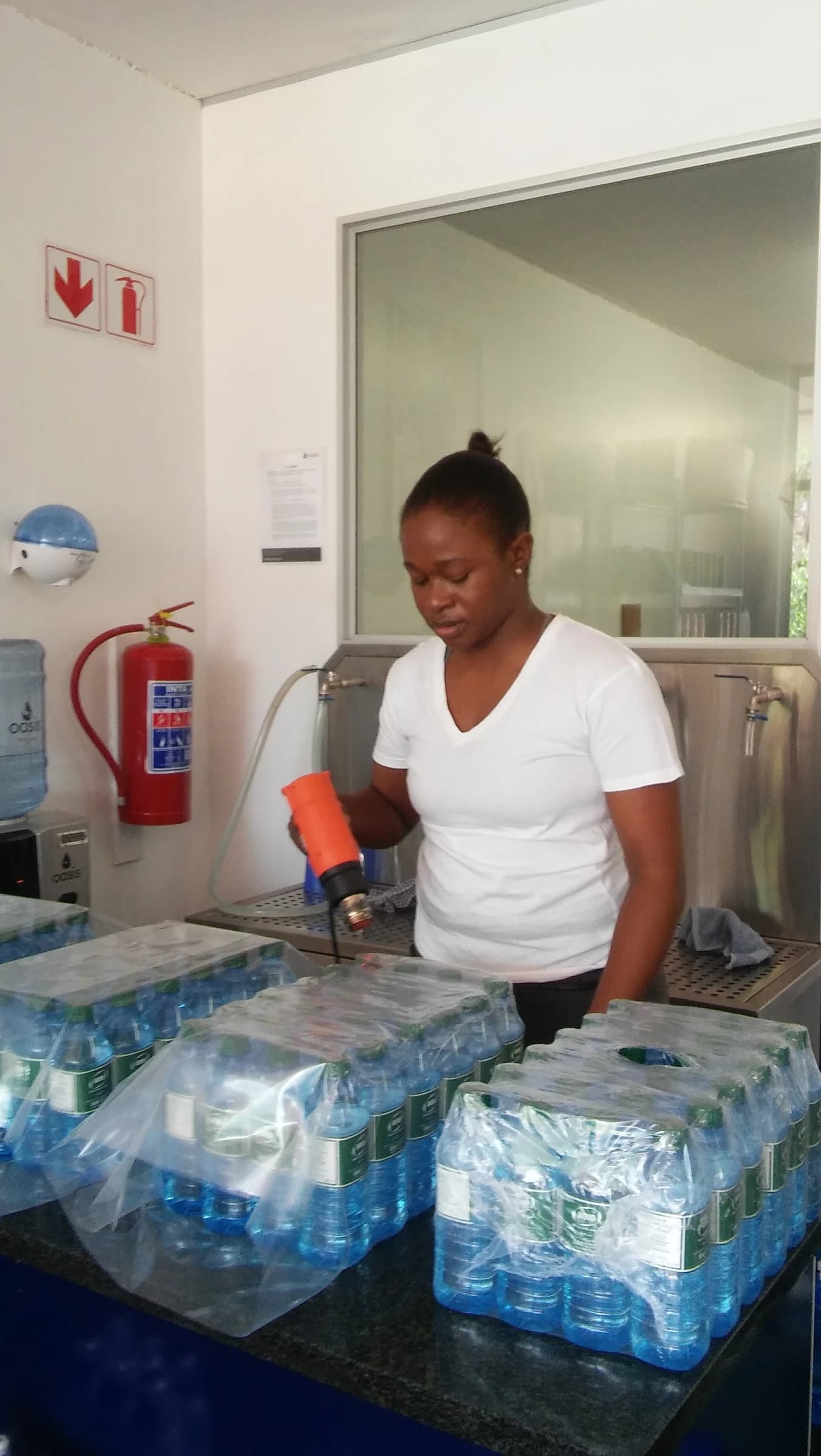 Woman in a bottling facility preparing cases of bottled water for packaging.