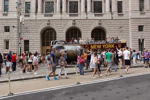 Tourists taking selfies of the Charging Bull monument in New York City.