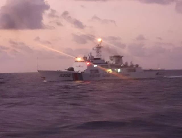 Chinese Coast Guard vessel 5205 in open water, emitting a laser beam from its bow.