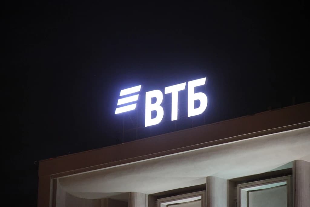Illuminated VTB Bank sign on VTB24 headquarters building at night in Moscow.