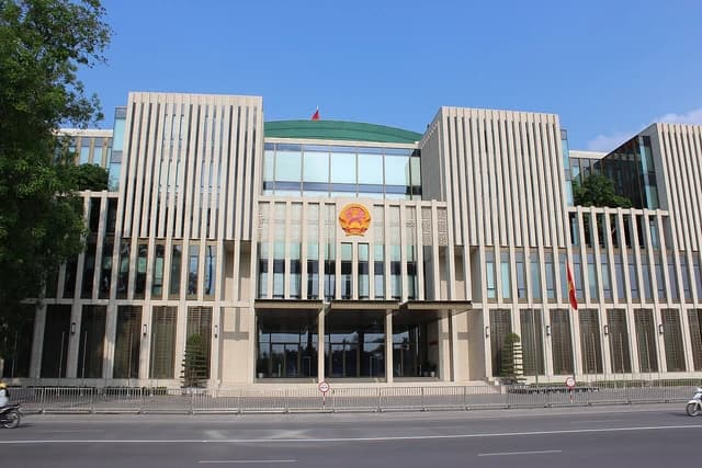 The modern building of the National Assembly of Vietnam with an emblem above the entrance.